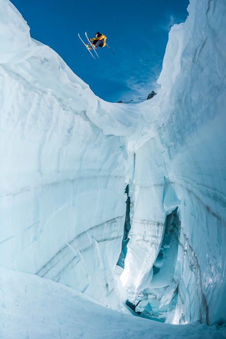 Esquiador saltando sobre enorme grieta helada