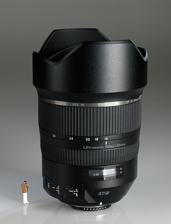 Pequeña figura de un fotógrafo, junto a un objetivo Tamron SP 15-30 mm f/2,8 Di VC USD