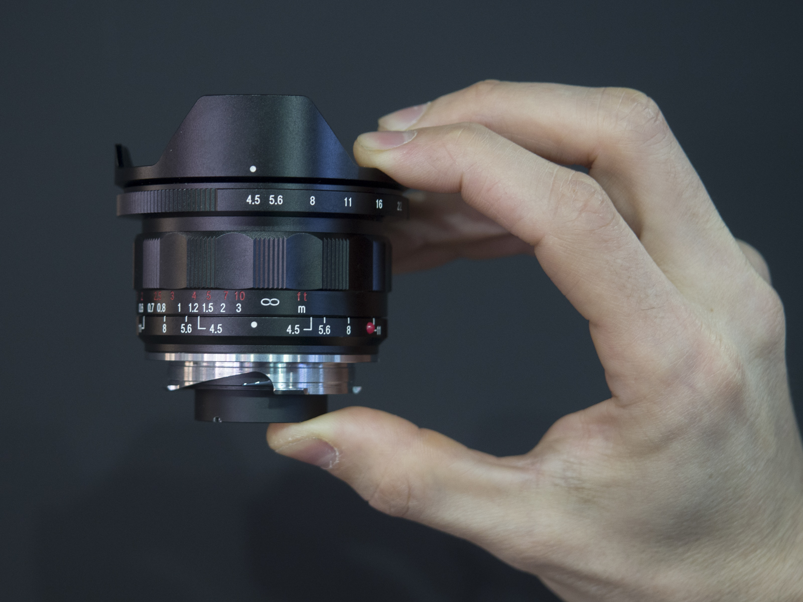 Una mano sostiene el pequeño objetivo Voigtländer VM Super Wide Heliar 15 mm f/4,5 Asph III
