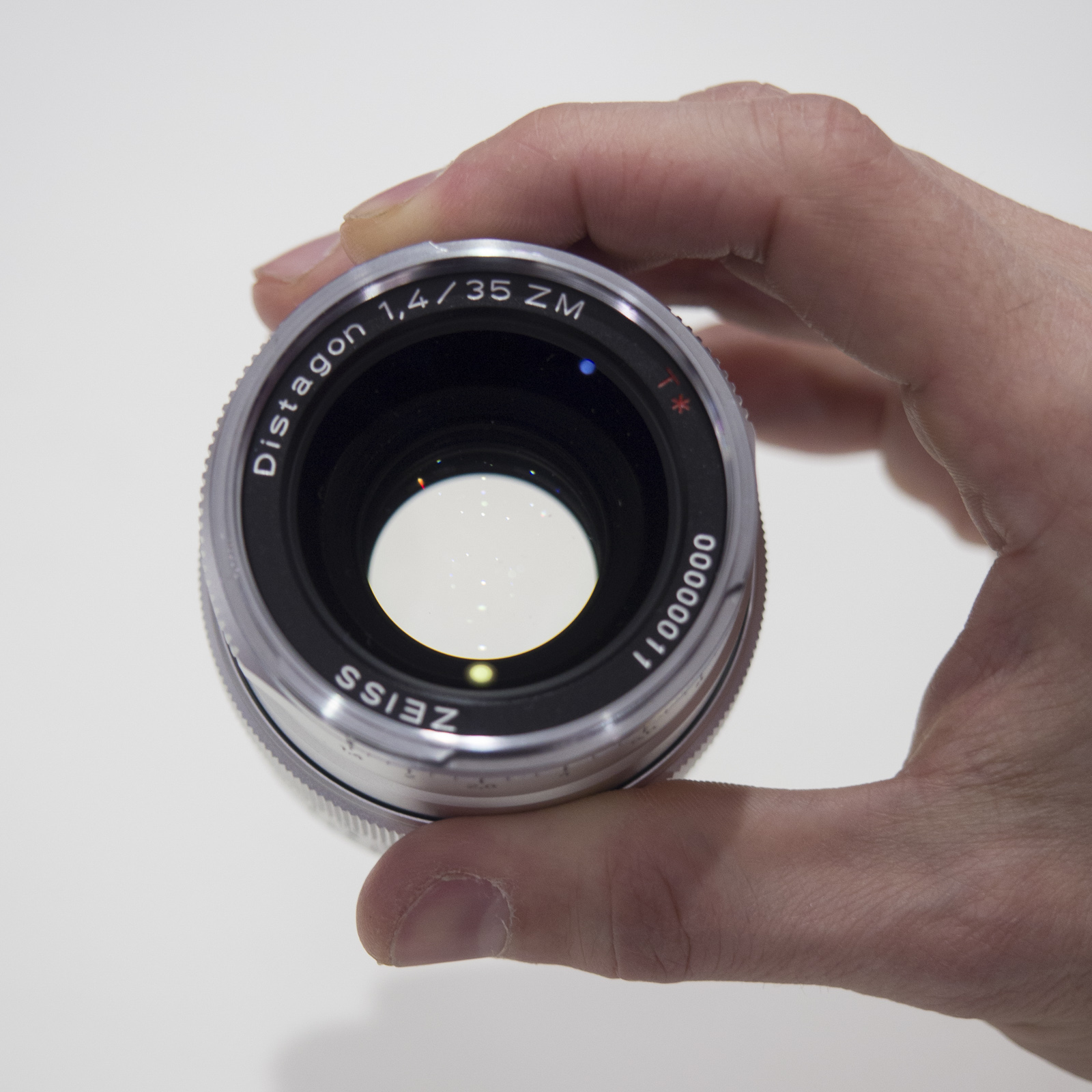 En la mano, de frente, un Zeiss Distagon T* 35 mm f/1,4 ZM