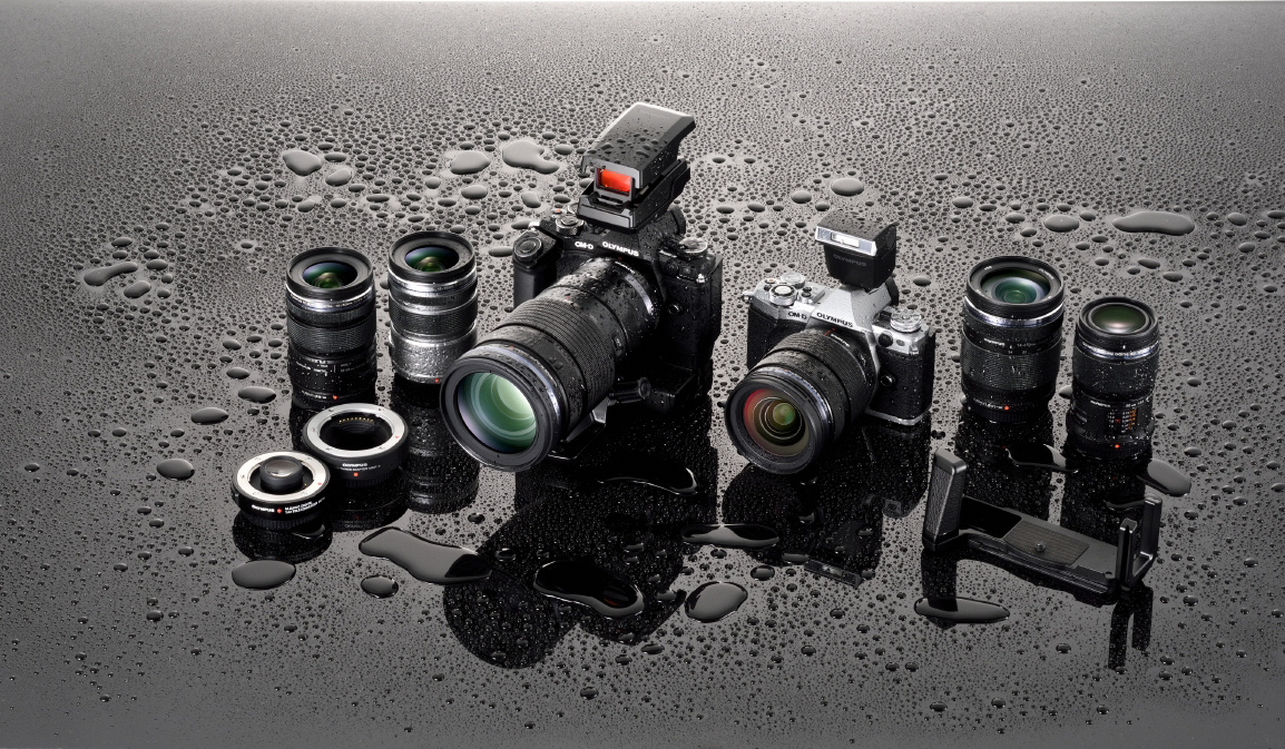 Conjunto actual de cuerpos, objetivos y accesorios Olympus a prueba de intemperie, cubiertos de gotas de agua