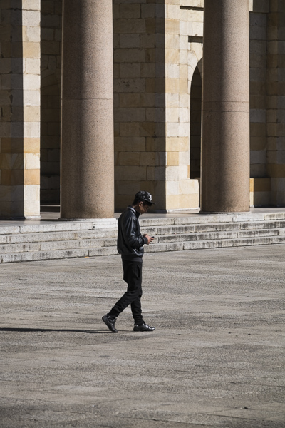 Laboral Ciudad de la Cultura, un joven consulta su móvil, con columnas del patio al fondo