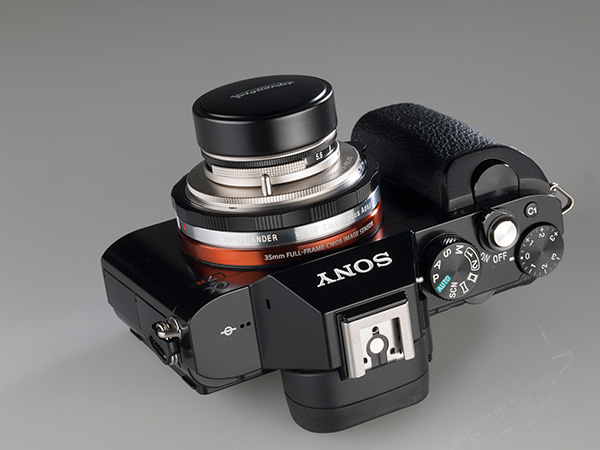 Se muestra el objetivo con el parasol "largo" y su tapa, acoplados sobre la Sony A7R, sobre su dorso