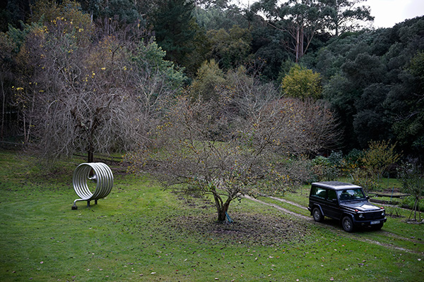 Campo con árbol, escultura de acero inoxidable y Mercedes Benz 4x4