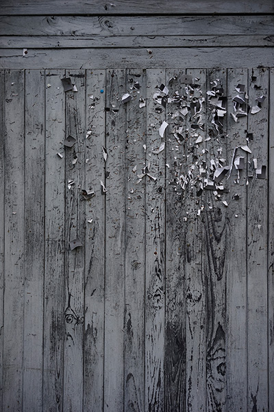 Puerta de madera gris, con multitud de restos de notas de papel, sujetas con grapas