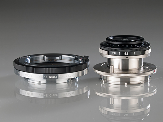 El objetivo Voigtländer Heliar 40 mm f/2,8 aparece en posición extendida junto al adaptador VM-E Close Focus