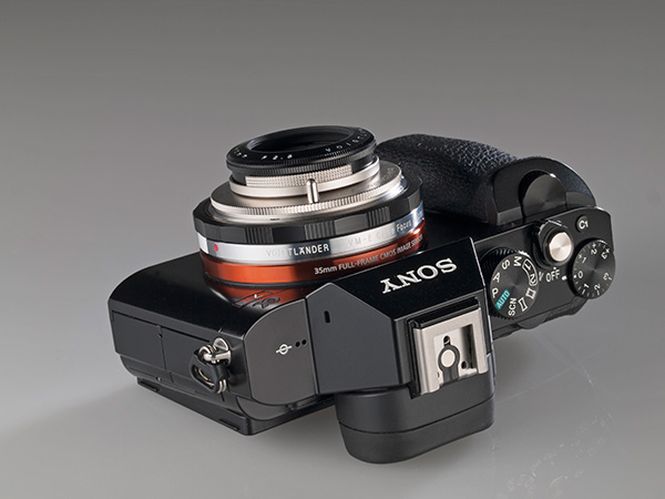 Se muestra el objetivo con el parasol corto, acoplado sobre la Sony A7R, sobre su dorso